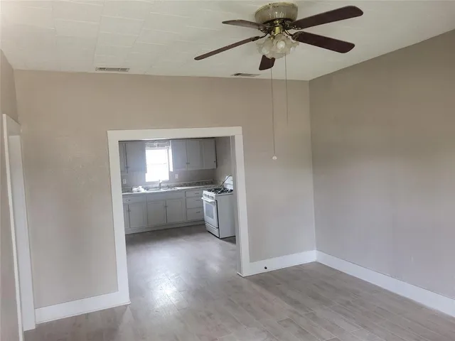 a view of an empty room and a kitchen