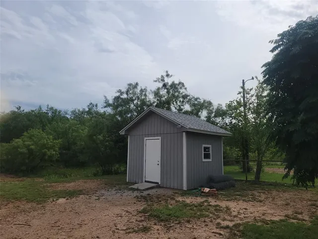 a view of a house with a yard and large trees