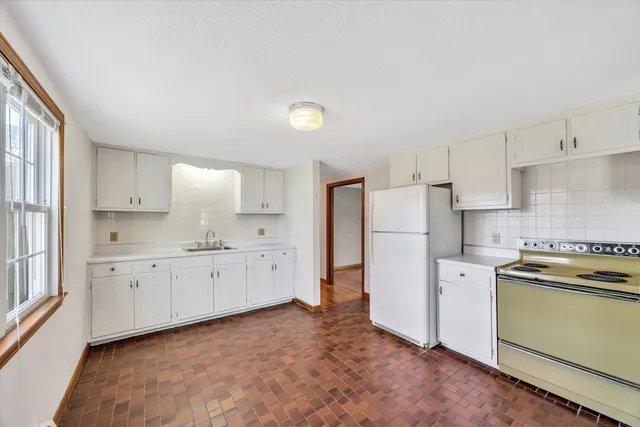 a kitchen with a refrigerator a stove top oven and white cabinets