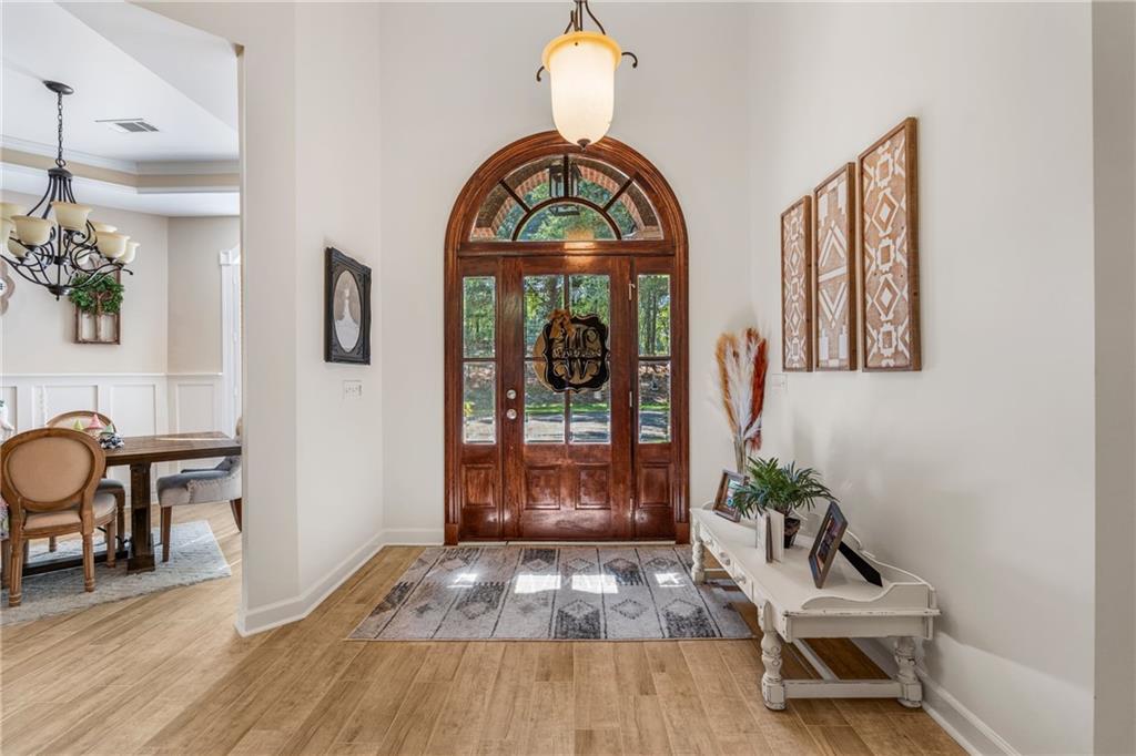 642 Nuckols Road Seale, AL 36875 - Photo 7 of 48 Arched wooden front entry door with glass panels, wood-finish flooring, and a decorative overhead light fixture