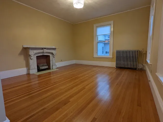 a view of empty room with wooden floor and fireplace