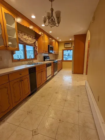 a large kitchen with stainless steel appliances a counter space a sink and cabinets