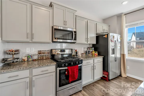 a kitchen with granite countertop a refrigerator stove and white cabinets