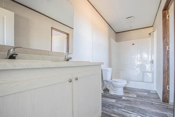 a bathroom with a granite countertop sink toilet a mirror and shower