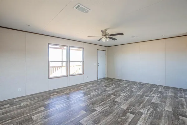 a view of an empty room with a window and wooden floor