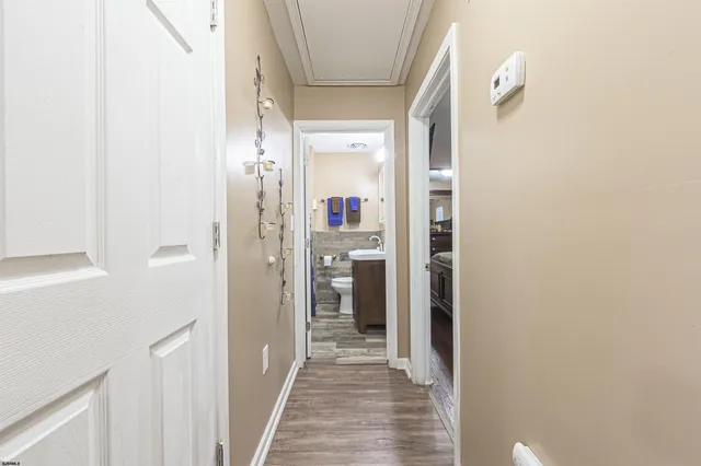 a view of a hallway with wooden floor and a bathroom
