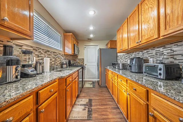 a large kitchen with stainless steel appliances granite countertop lots of counter space and wooden floor