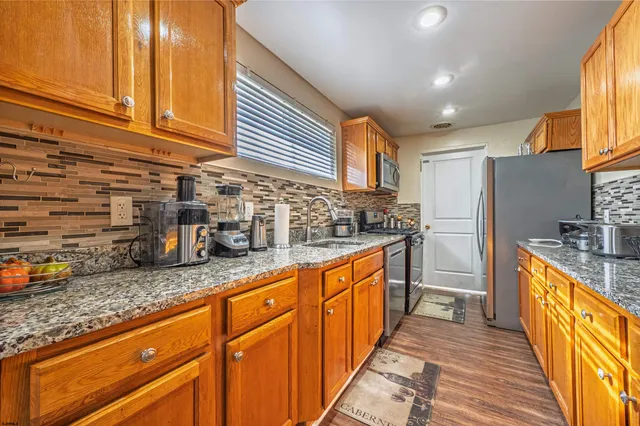 a kitchen with granite countertop a sink a counter space cabinets and stainless steel appliances
