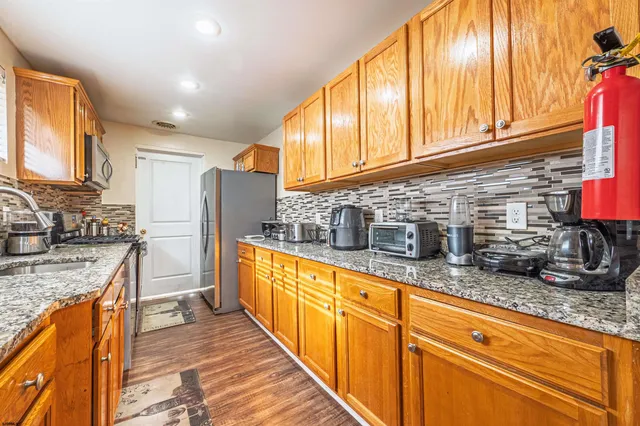 a kitchen with granite countertop stainless steel appliances a sink a counter top space and cabinets