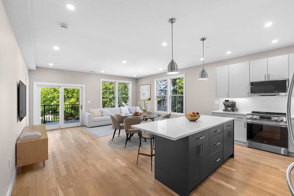 40 Waverly Street, Unit 2 Boston, MA 02135 - Photo 2 of 7 a open kitchen with stainless steel appliances granite countertop a stove top oven a sink dishwasher a dining table and chairs with wooden floor