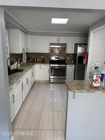a kitchen with stainless steel appliances granite countertop a sink dishwasher stove and refrigerator