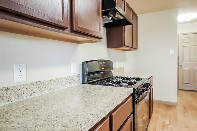 a kitchen with granite countertop a stove and a wooden floor