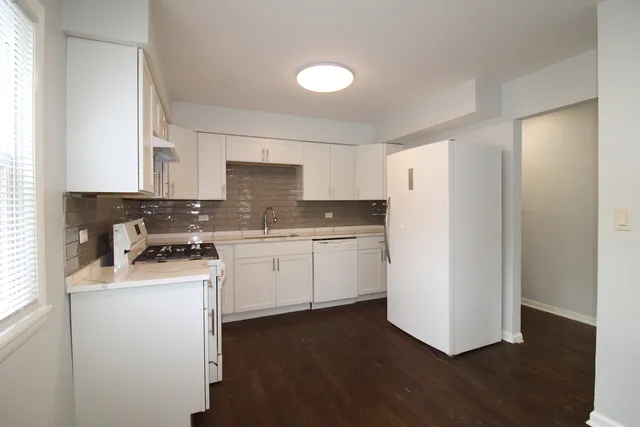a kitchen with granite countertop white cabinets and white appliances