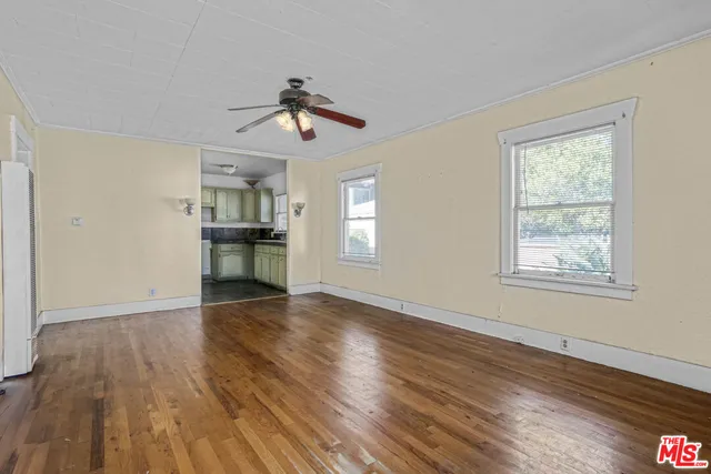 a view of empty room with wooden floor and ceiling fan