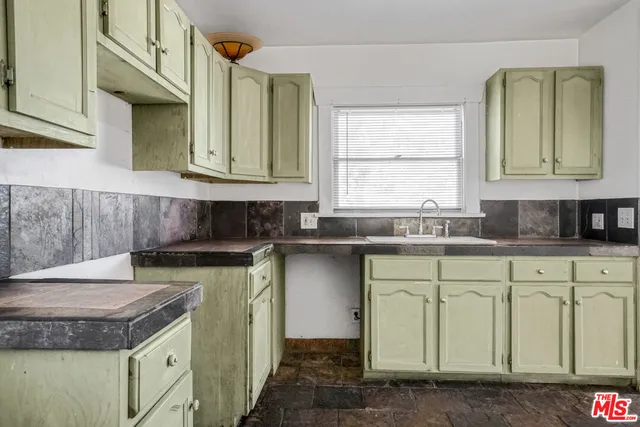 a kitchen with granite countertop a sink a stove and cabinets