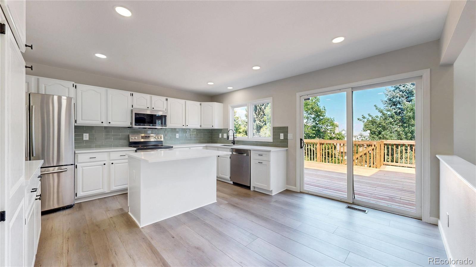 6265 Cornell Court Highlands Ranch, CO 80130 - Photo 5 of 41 a kitchen with white cabinets and stainless steel appliances