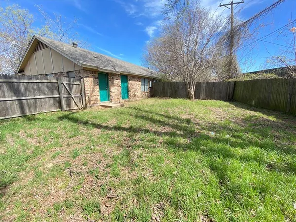 a view of backyard of house with wooden fence