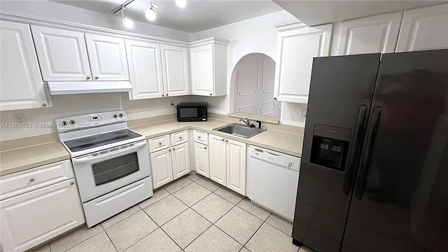 a kitchen with a refrigerator sink and cabinets