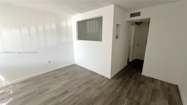 an empty room with wooden floor and a ceiling fan