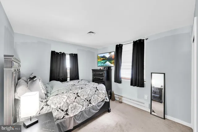 a bedroom with a bed large mirror on dresser and a window