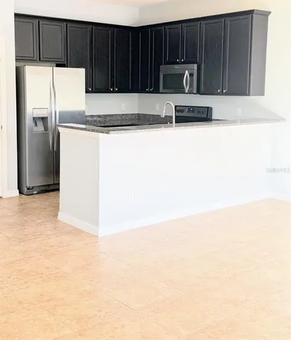 a kitchen with granite countertop a refrigerator oven a stove with wooden cabinets