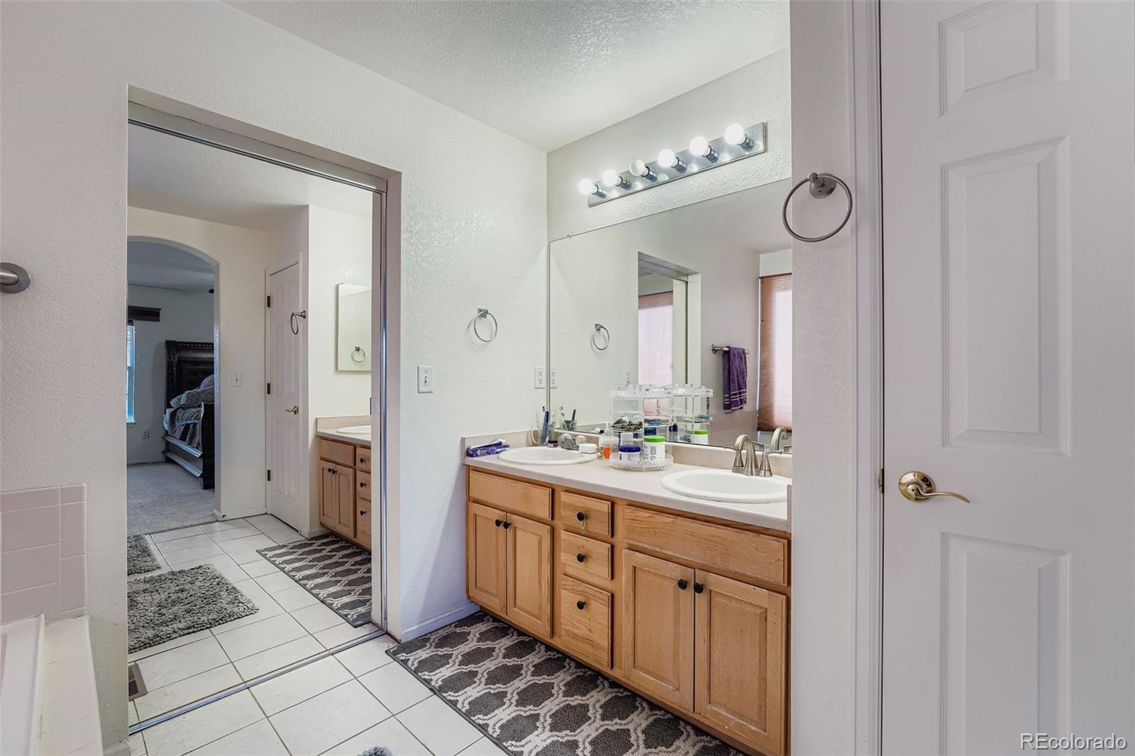 2743 South Waco Way Aurora, CO 80013 - Photo 19 of 28 a spacious bathroom with a double vanity sink a mirror and a shower