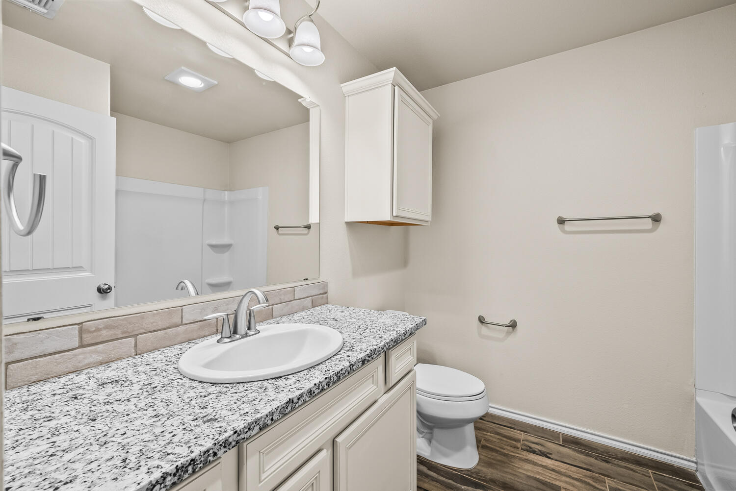 7027 37th Street Lubbock, TX 79407 - Photo 24 of 36 a bathroom with a granite countertop sink a toilet and a mirror
