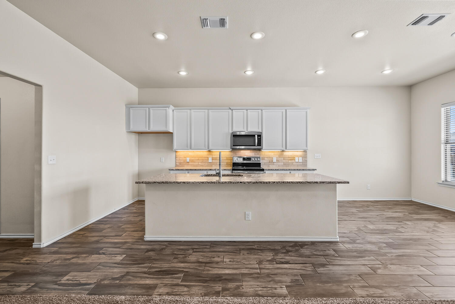 7027 37th Street Lubbock, TX 79407 - Photo 7 of 36 a kitchen with stainless steel appliances granite countertop a sink a stove a refrigerator and a microwave