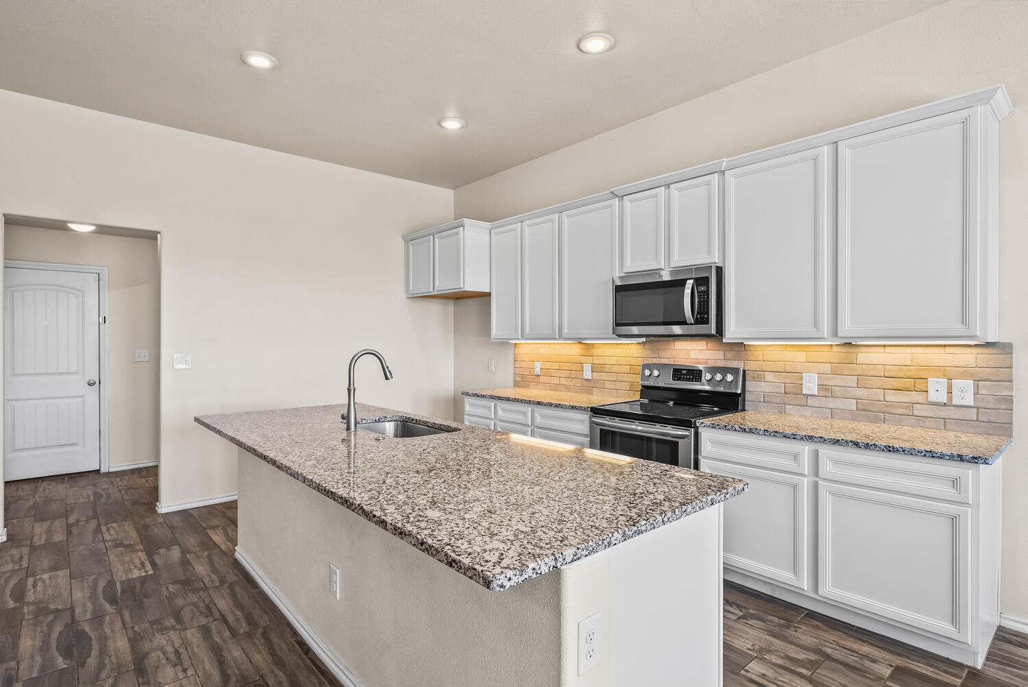 7027 37th Street Lubbock, TX 79407 - Photo 8 of 36 a kitchen with granite countertop a sink dishwasher stove and white cabinets with wooden floor