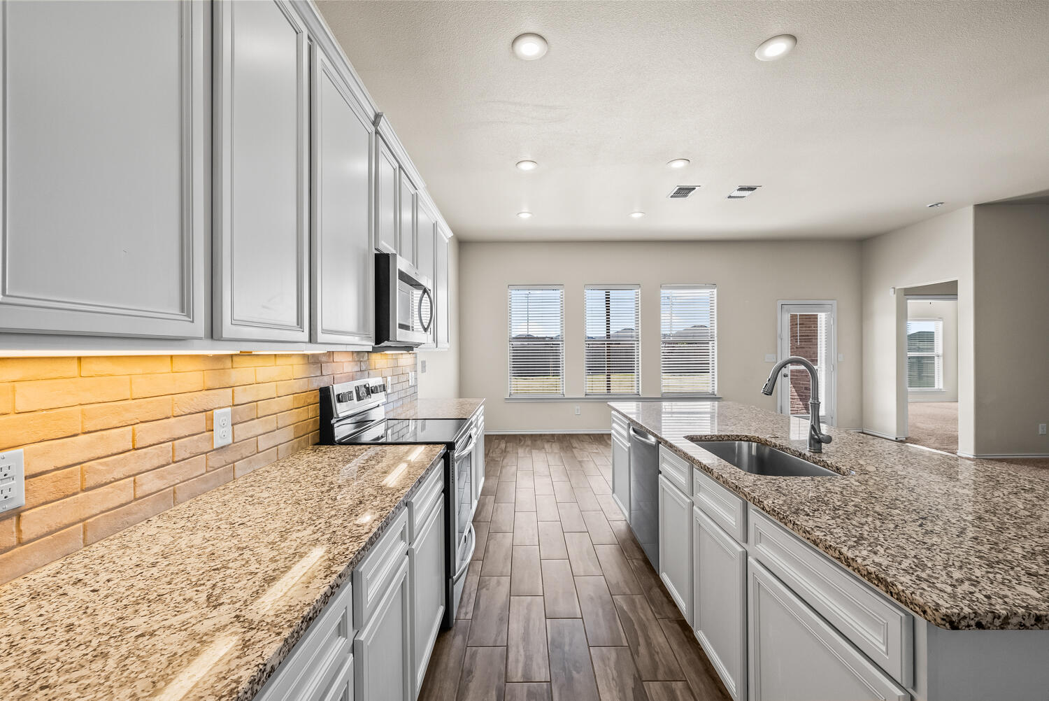 7027 37th Street Lubbock, TX 79407 - Photo 9 of 36 a large kitchen with granite countertop a sink and dishwasher stove top oven