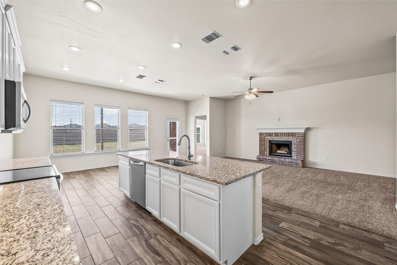7027 37th Street Lubbock, TX 79407 - Photo 10 of 36 a large white kitchen with granite countertop a stove and a sink