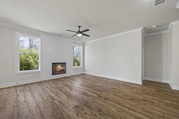 a view of an empty room with a window and wooden floor