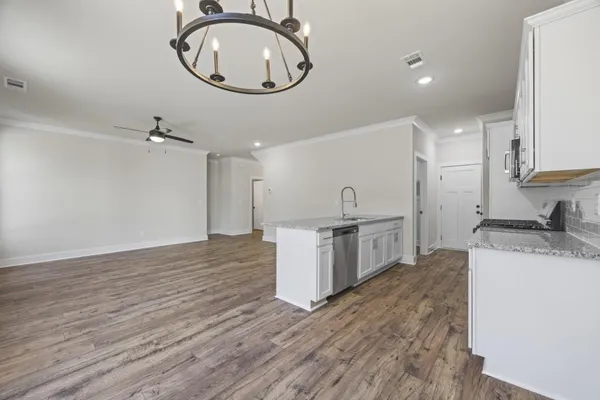 a kitchen with granite countertop a sink stove and cabinets