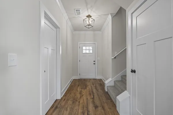 a view of a hallway with wooden floor and a bathroom