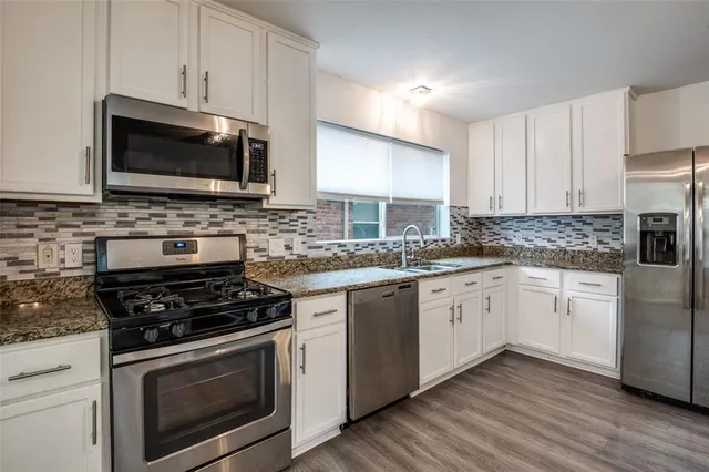 a kitchen with cabinets stainless steel appliances a sink and a stove