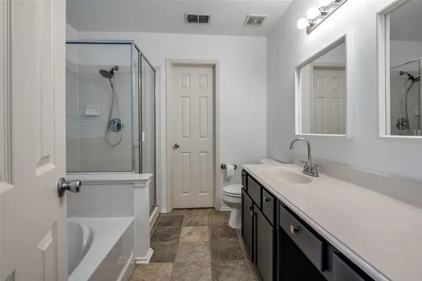 a bathroom with a tub sink vanity granite and shower