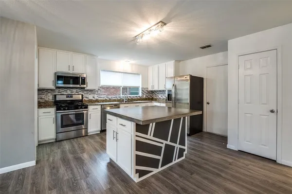 a kitchen with a stove a refrigerator and a microwave
