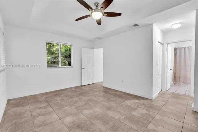 a view of an empty room and window and a ceiling fan