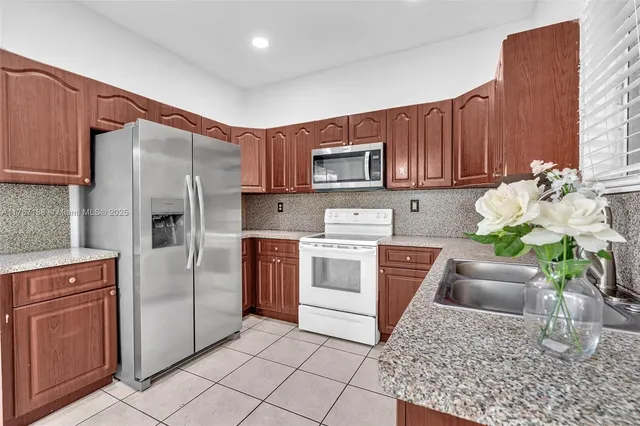 a kitchen with stainless steel appliances granite countertop a refrigerator sink and stove