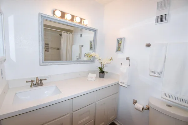 a bathroom with a sink vanity granite and toilet
