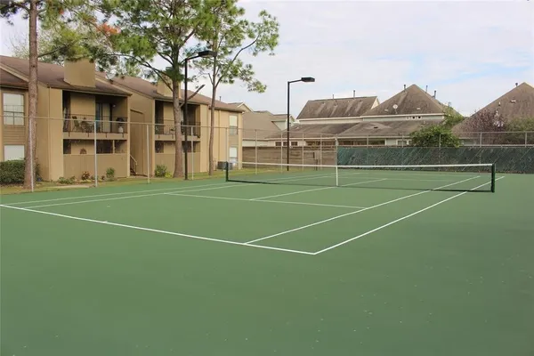 a view of a tennis ground with large trees