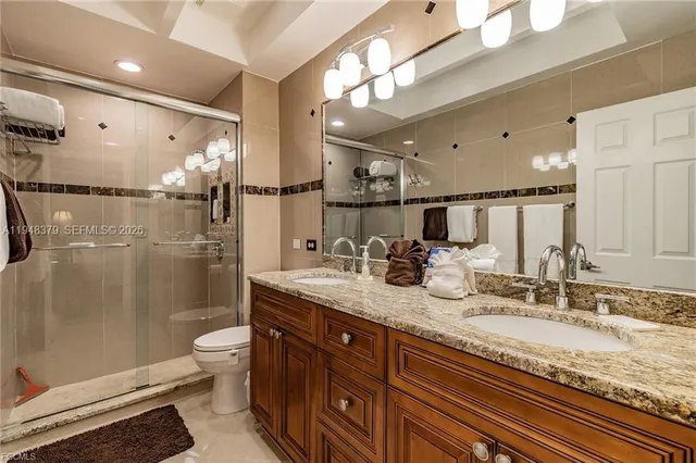 a bathroom with a granite countertop sink a toilet a mirror and shower