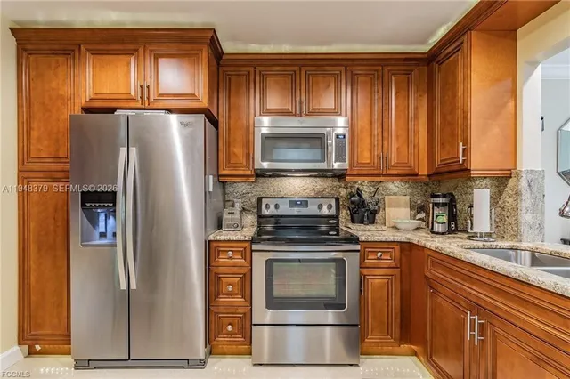 a kitchen with granite countertop a refrigerator stove and microwave