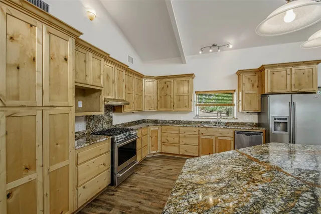 a kitchen with stainless steel appliances granite countertop a sink stove and refrigerator