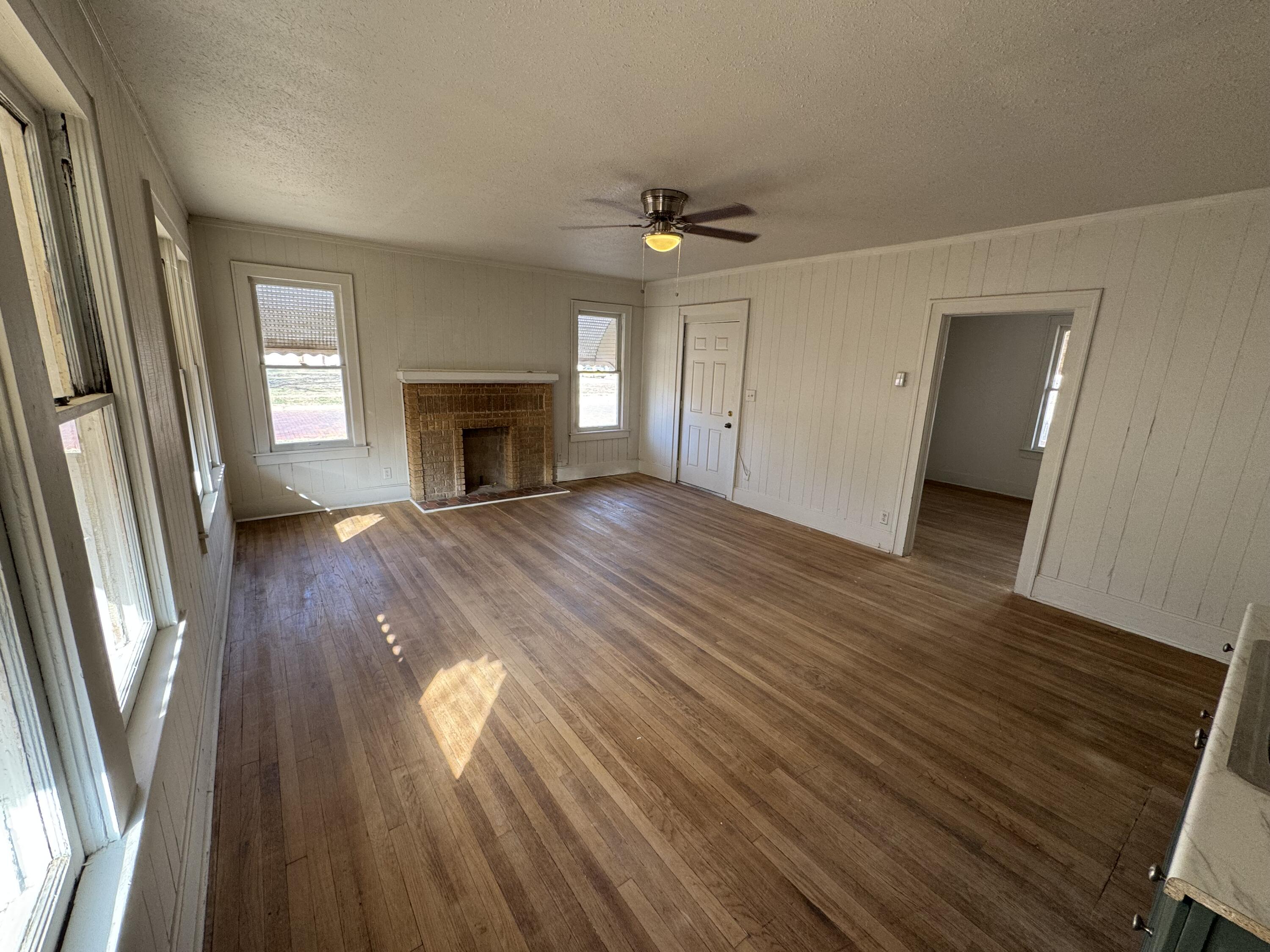 1903 16th Street, Unit A Lubbock, TX 79401 - Photo 6 of 7 an empty room with wooden floor fireplace and windows