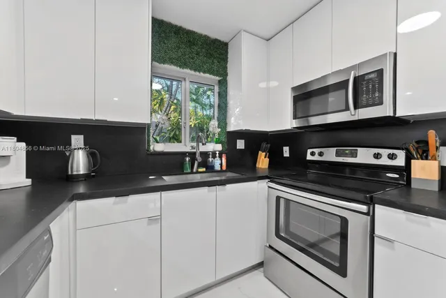 a kitchen with stainless steel appliances granite countertop white cabinets granite counter tops and a window