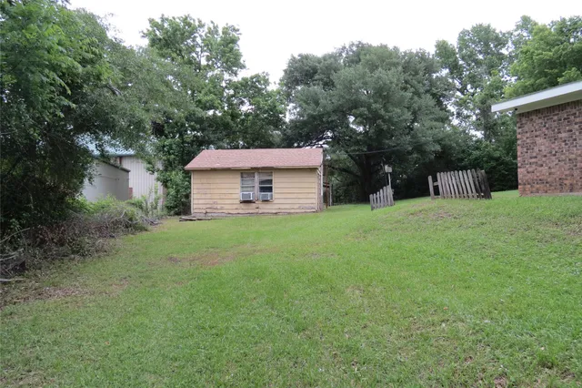 a backyard of a house with table and chairs plants and large tree