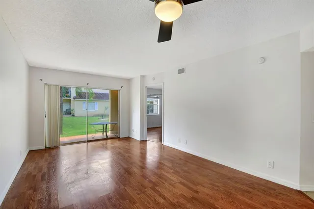 a view of an empty room with wooden floor and windows