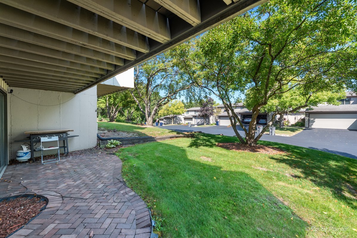 1104 Florimond Drive, Unit 1104 Elgin, IL 60123 - Photo 21 of 28 a view of a backyard with table and chairs and a barbeque