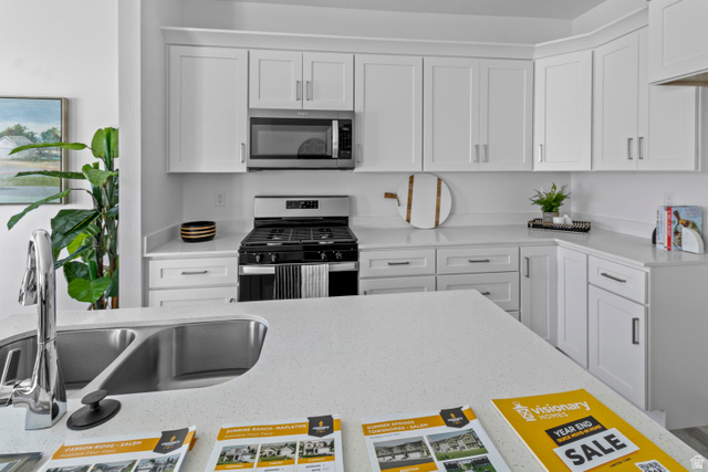 1264 West 500 South, Unit 320 Logan, UT 84321 - Photo 8 of 39 Modern kitchen featuring white shaker cabinetry, stainless steel appliances, and light-toned countertops